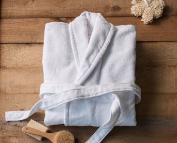 bathrobe bath soap and loofah brush behind wooden table