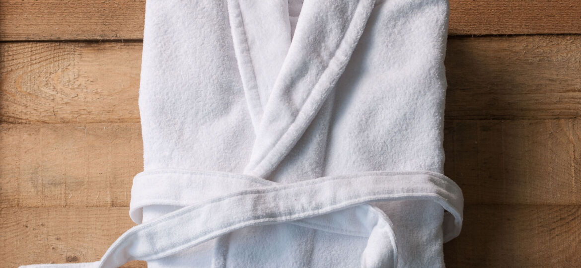 bathrobe bath soap and loofah brush behind wooden table